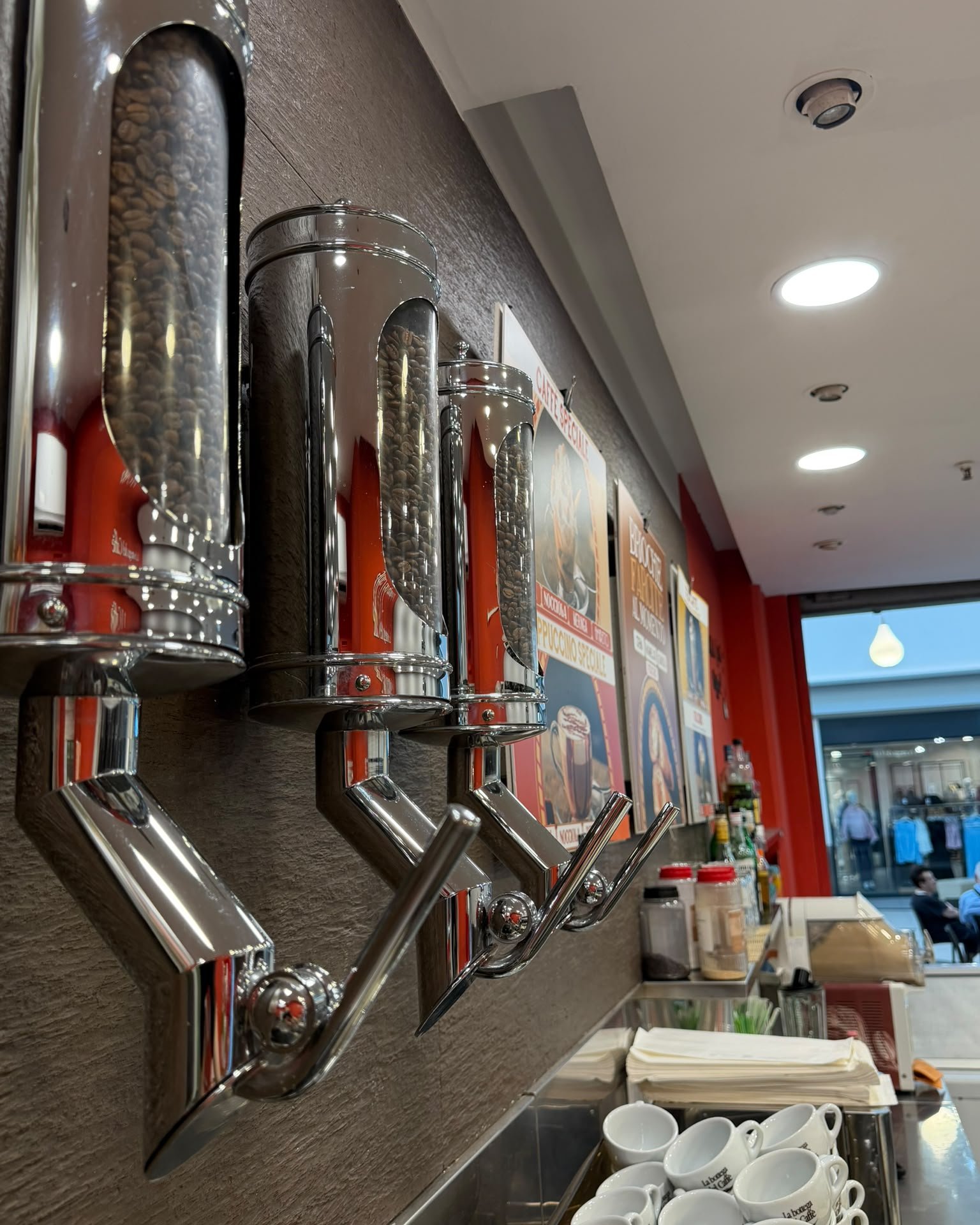 Dispenser di chicchi di caffè e tazzine al bar caffetteria nel centro commerciale di Mantova